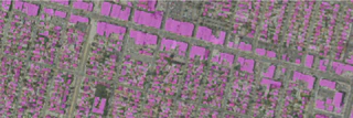 A grayscale satellite image of an urban area with building footprints highlighted in purple.